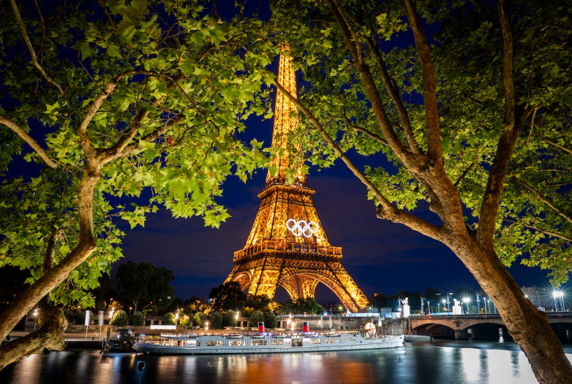 The Eiffel Tower lit up at night while a boat floats in front of it
along the Seine